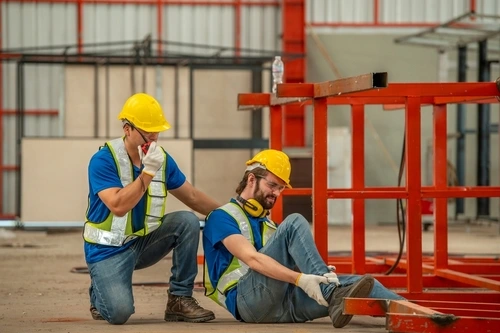 a construction worker talks on the radio next to another worker who has been injured