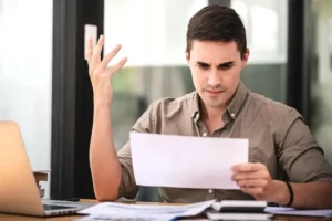 Injured worker in Miami reviewing denied workers compensation claim letter with medical bills and paperwork on desk