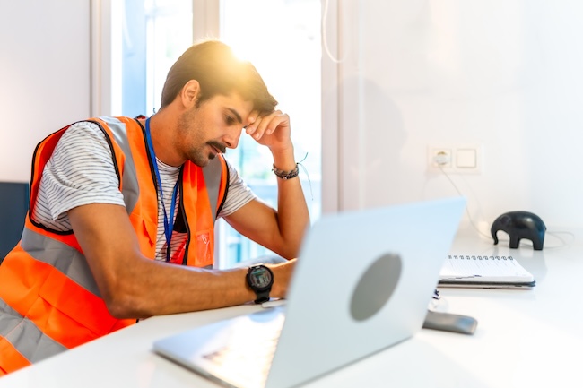 Worried Florida worker at desk reviewing workers compensation claim documents after employer retaliation"