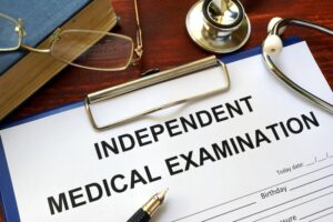 An independent medical examination form is on the desk of a lawyer from WorkInjuryRights.com in Florida.