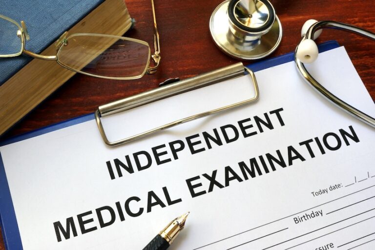 An independent medical examination form is on the desk of a lawyer from WorkInjuryRights.com in Florida.