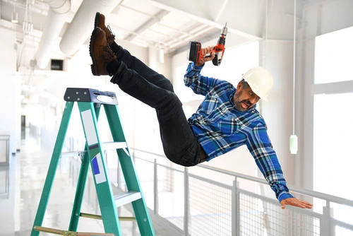 Construction worker with a drill falling from a ladder